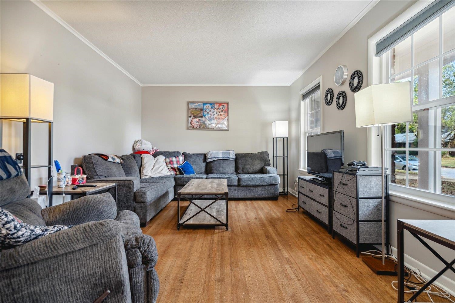 Living room with light wood-type flooring and ornamental molding