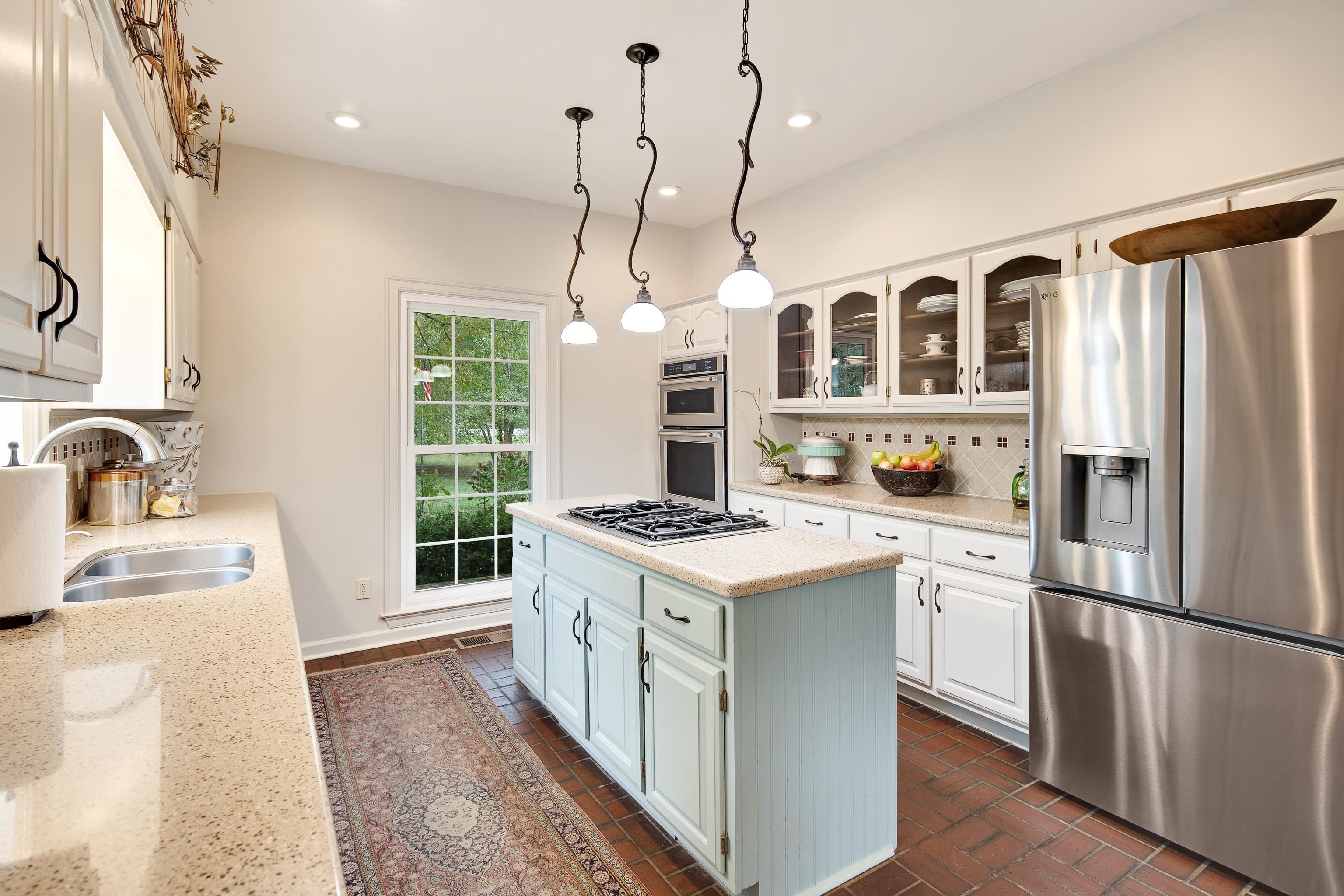 Kitchen with sink, a center island, stainless steel appliances, decorative light fixtures, and white cabinets