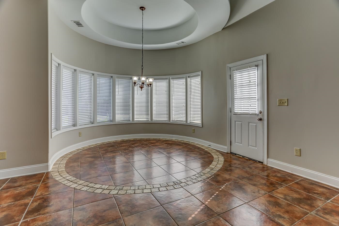 Entryway featuring a chandelier, a raised ceiling, and dark tile patterned floors