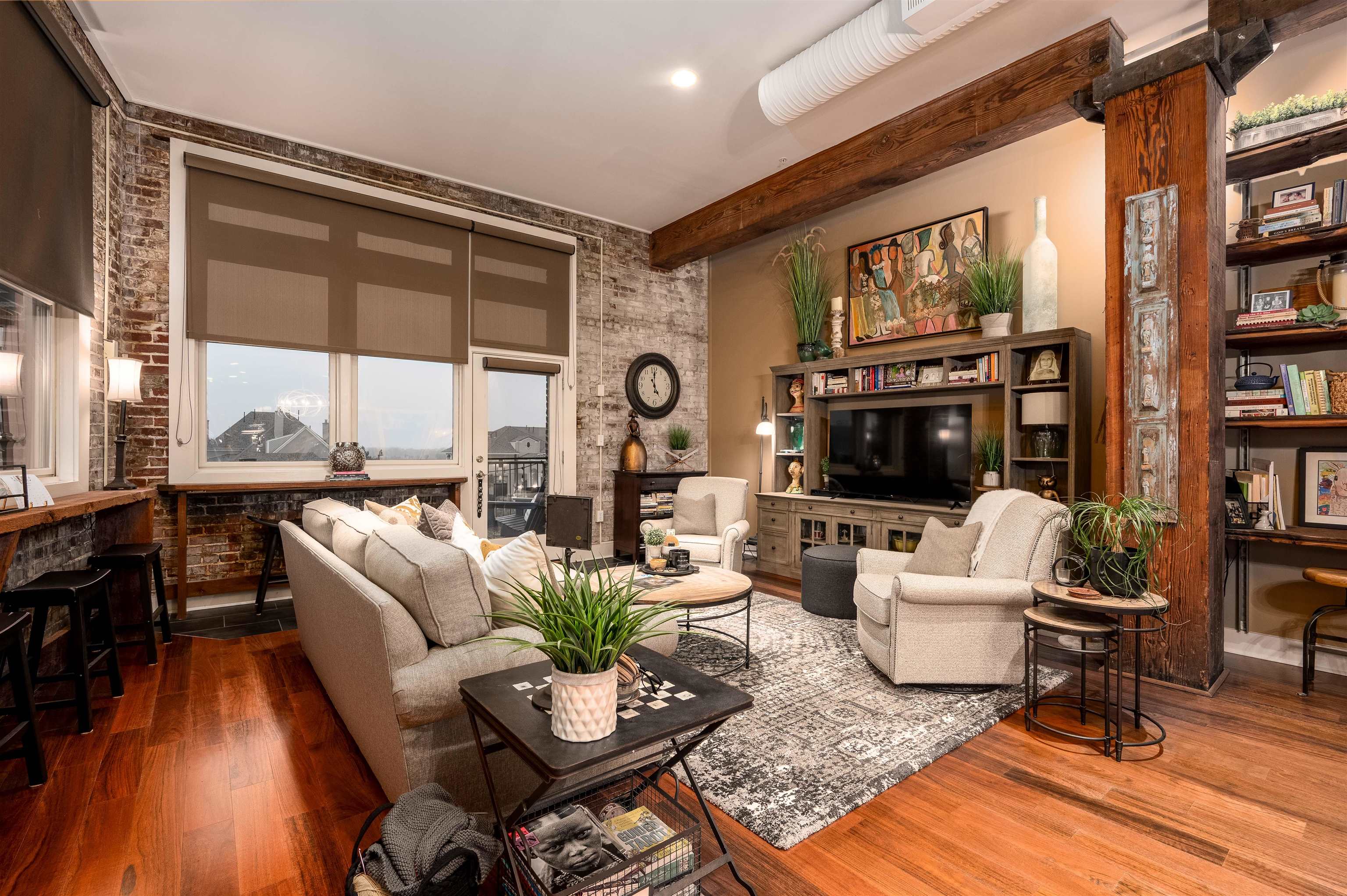 Living room with brick wall, wood-type flooring, and beams