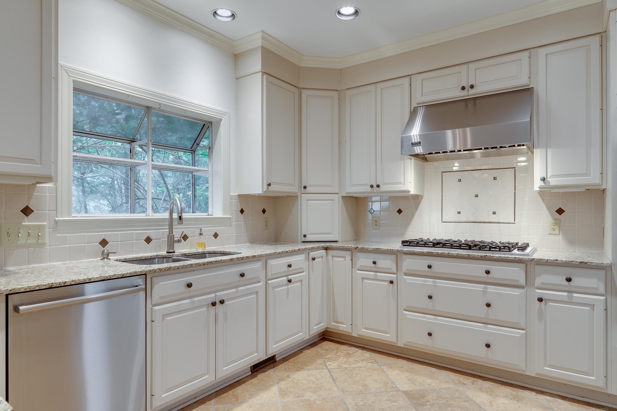 Kitchen featuring white cabinets, decorative backsplash, stainless steel appliances, and sink