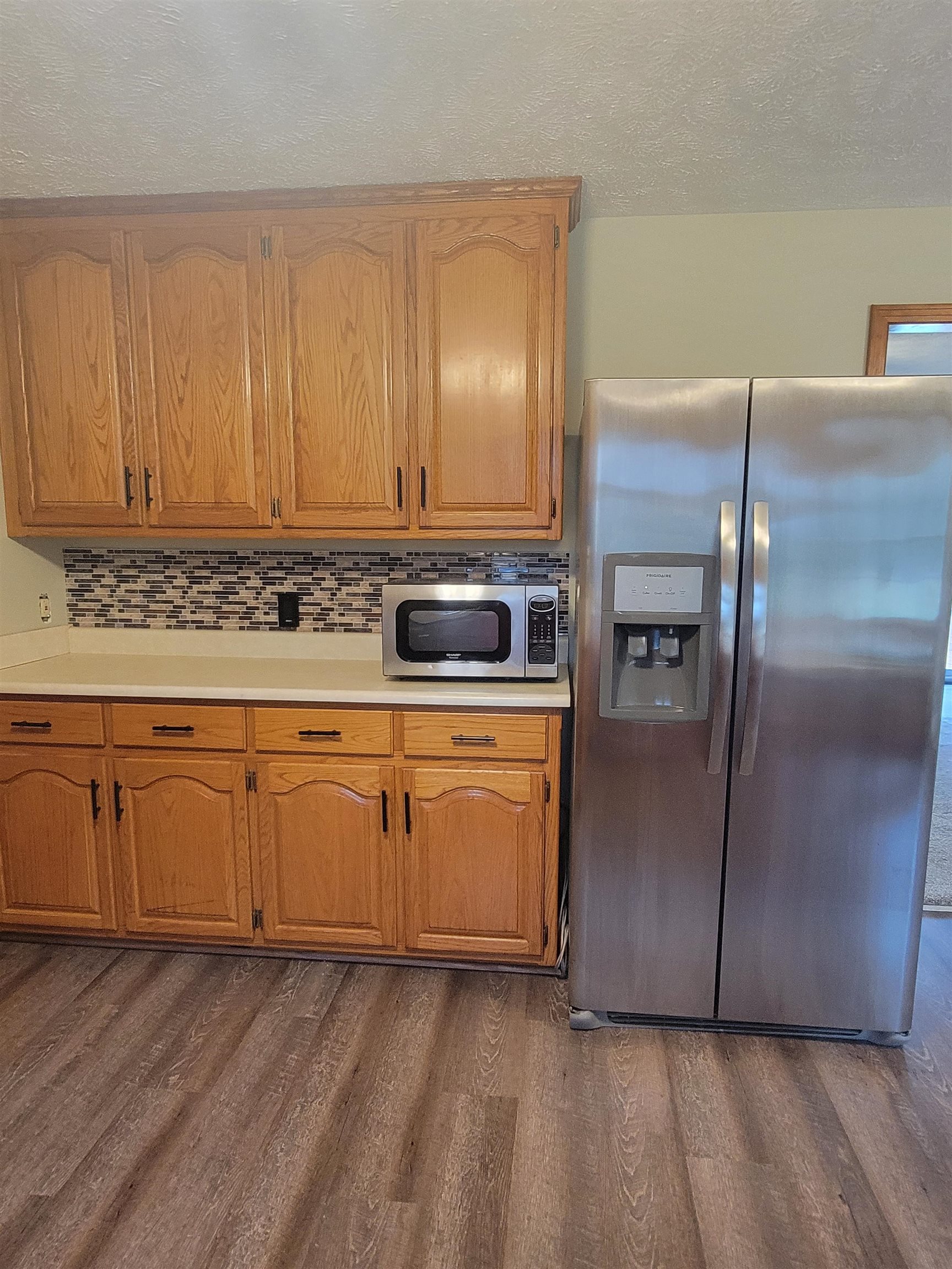 Kitchen featuring decorative backsplash, appliances with stainless steel finishes, a textured ceiling, and dark hardwood / wood-style flooring