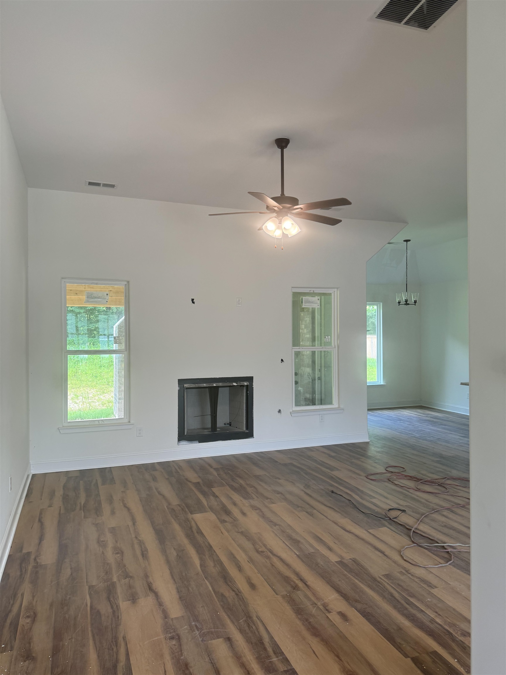 Family room featuring ceiling fan with notable chandelier and dark wood-type flooring