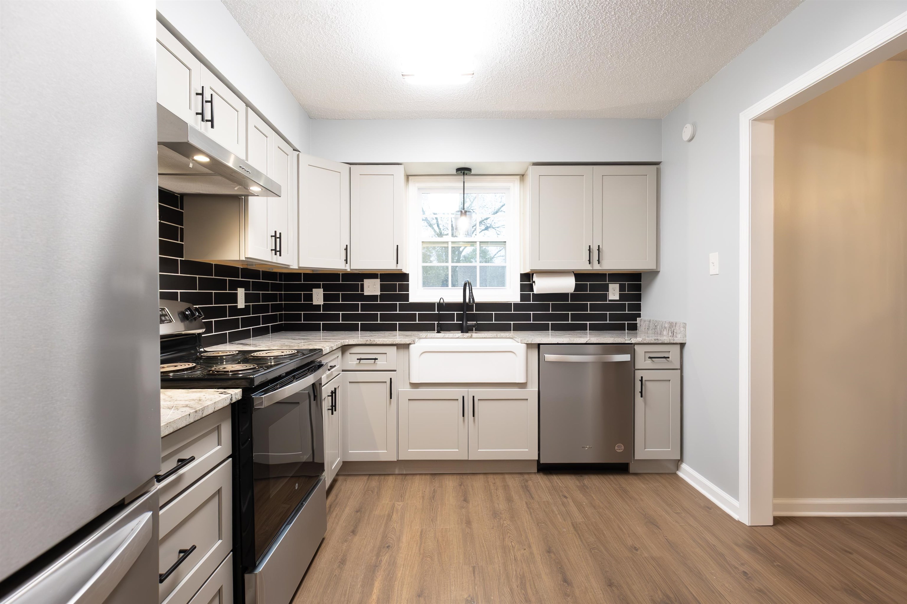 Kitchen featuring light stone counters, stainless steel appliances, light wood-type flooring, a textured ceiling, and sink