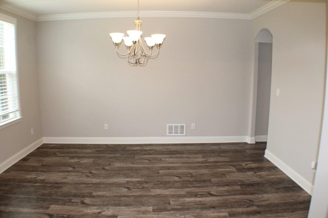 Spare room with ornamental molding and dark hardwood / wood-style floors