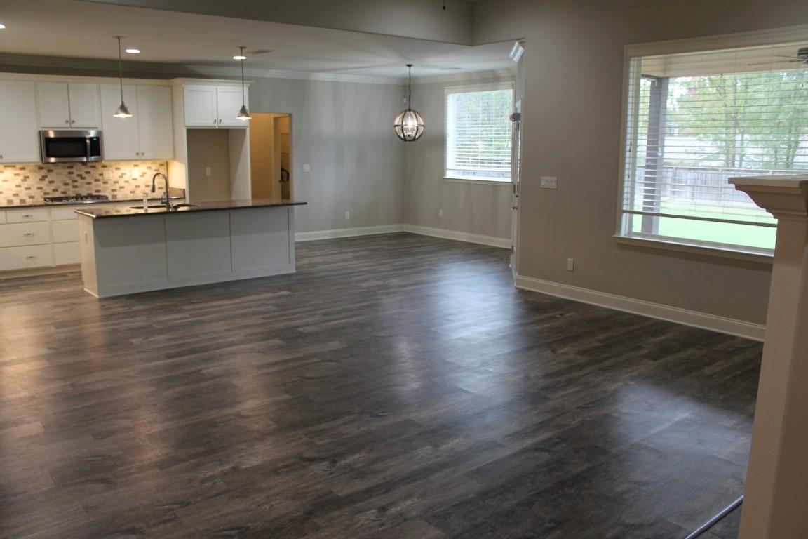 Kitchen featuring stainless steel appliances, white cabinetry, sink, dark wood-type flooring, and pendant lighting