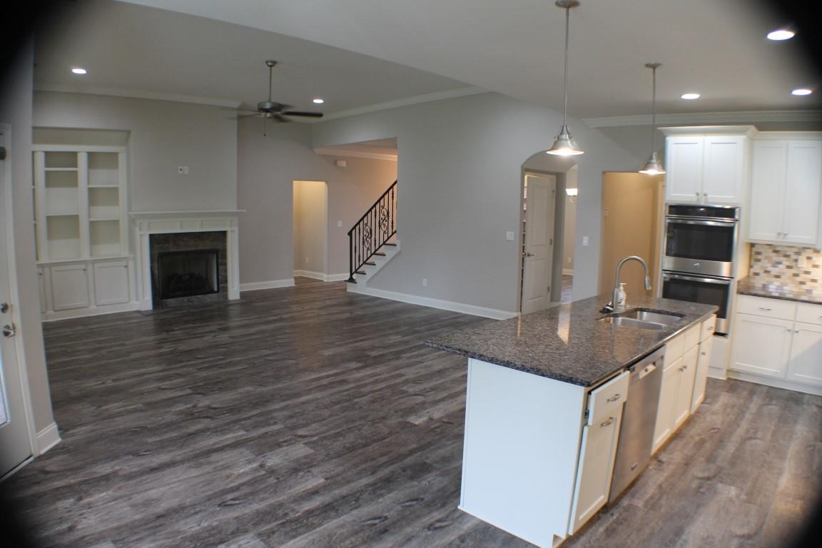 Kitchen with sink, appliances with stainless steel finishes, dark stone counters, white cabinets, and dark hardwood / wood-style flooring