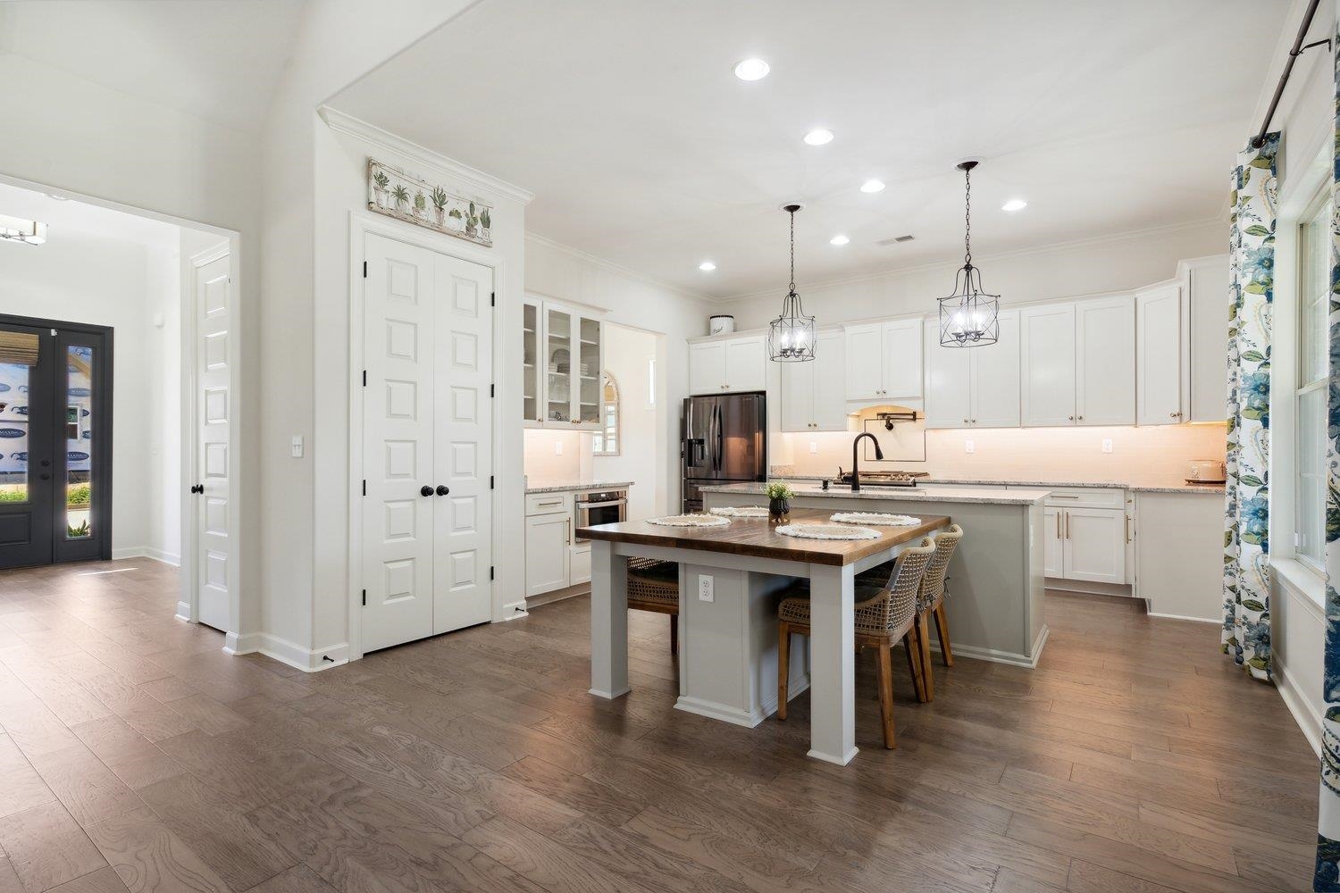 Another view of the kitchen shows off the beautiful wood floors, white cabinets & center island with deep sink and hand-crafted, custom made, built-in table that seats four.  Built in Microwave, under lighting and kitchen pantry.   Chairs are negotiable.