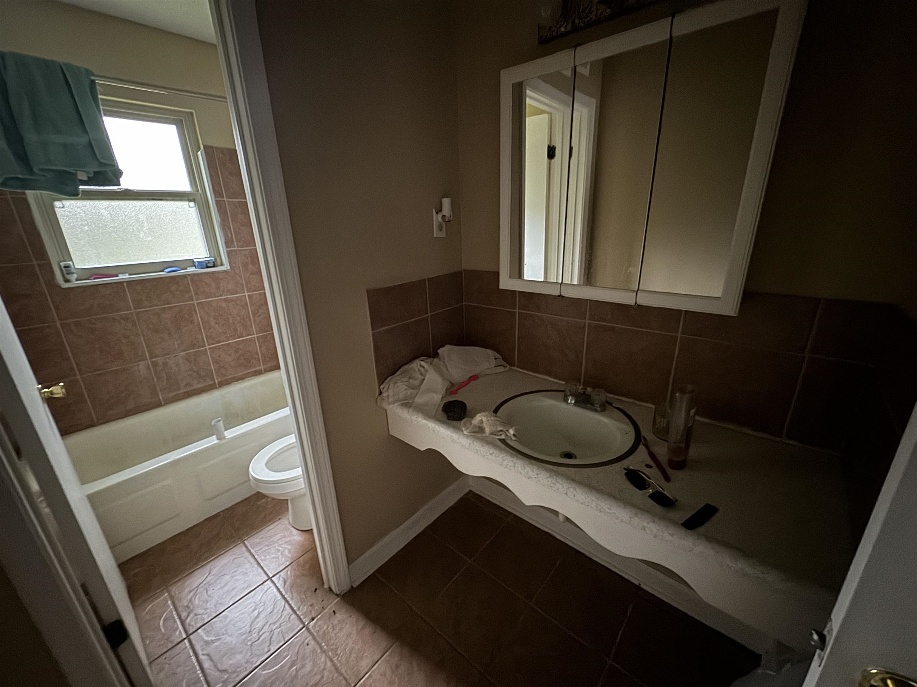 Bathroom with tile patterned flooring, sink, backsplash, and toilet