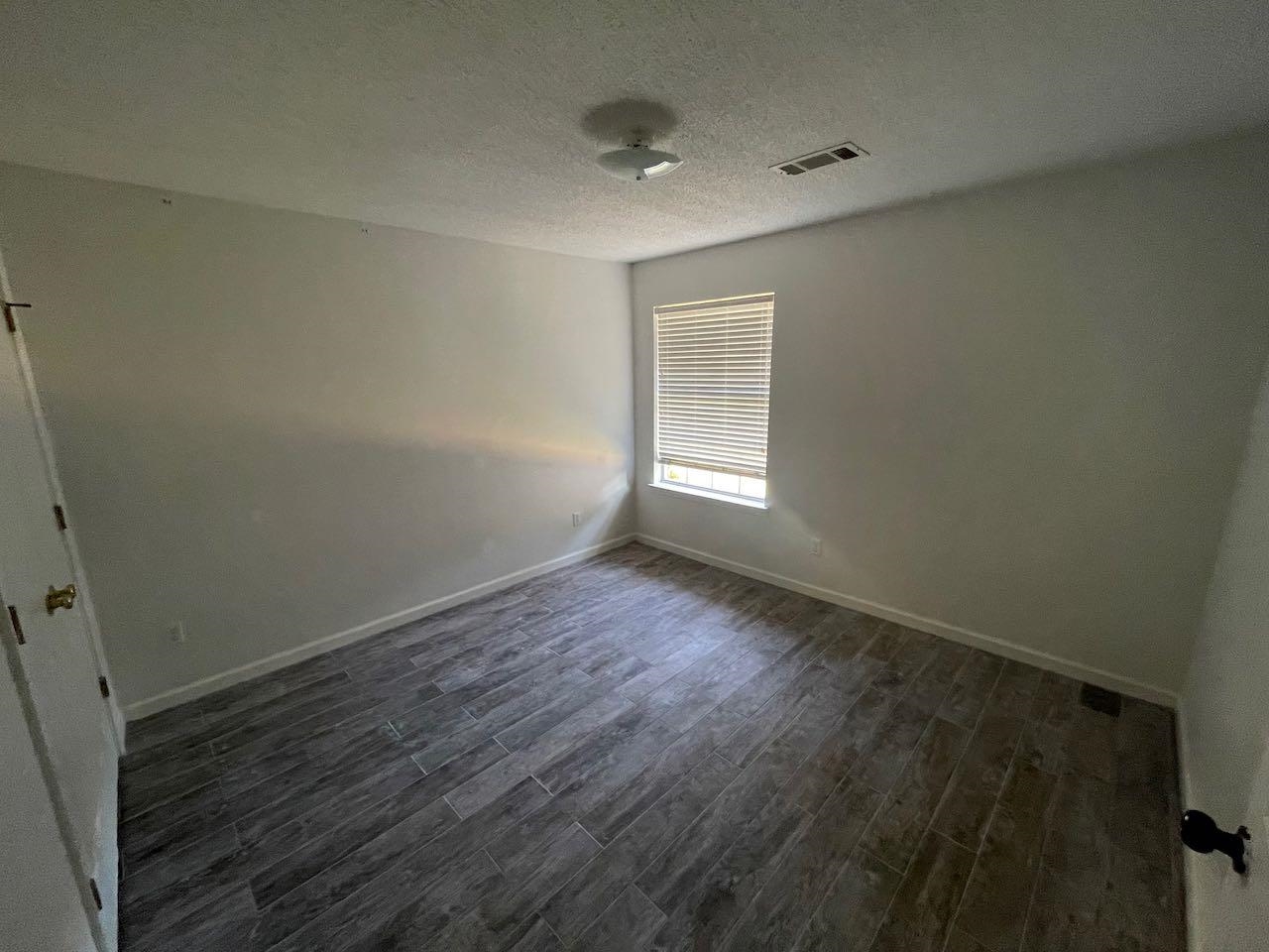 Unfurnished room with a textured ceiling and hardwood / wood-style flooring