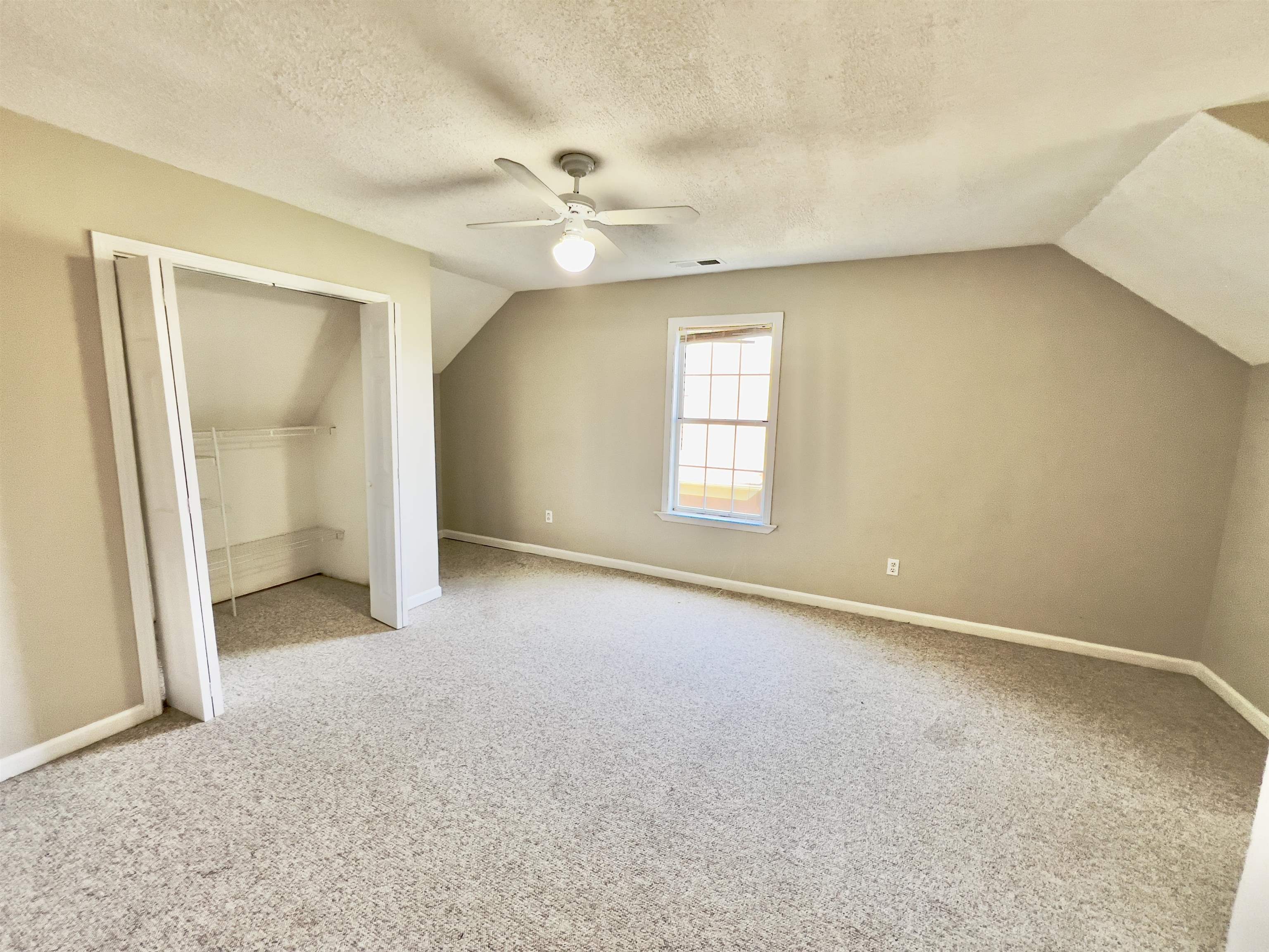 Bonus room with light carpet, lofted ceiling, ceiling fan, and a textured ceiling