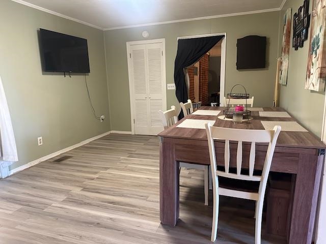 Dining room with crown molding and light hardwood / wood-style flooring