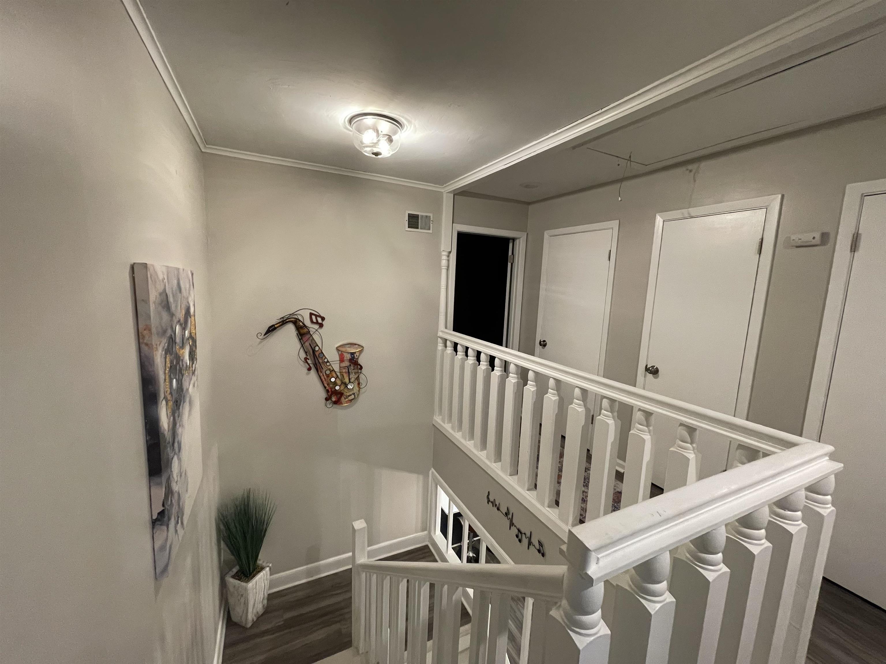 Staircase with wood-type flooring and ornamental molding