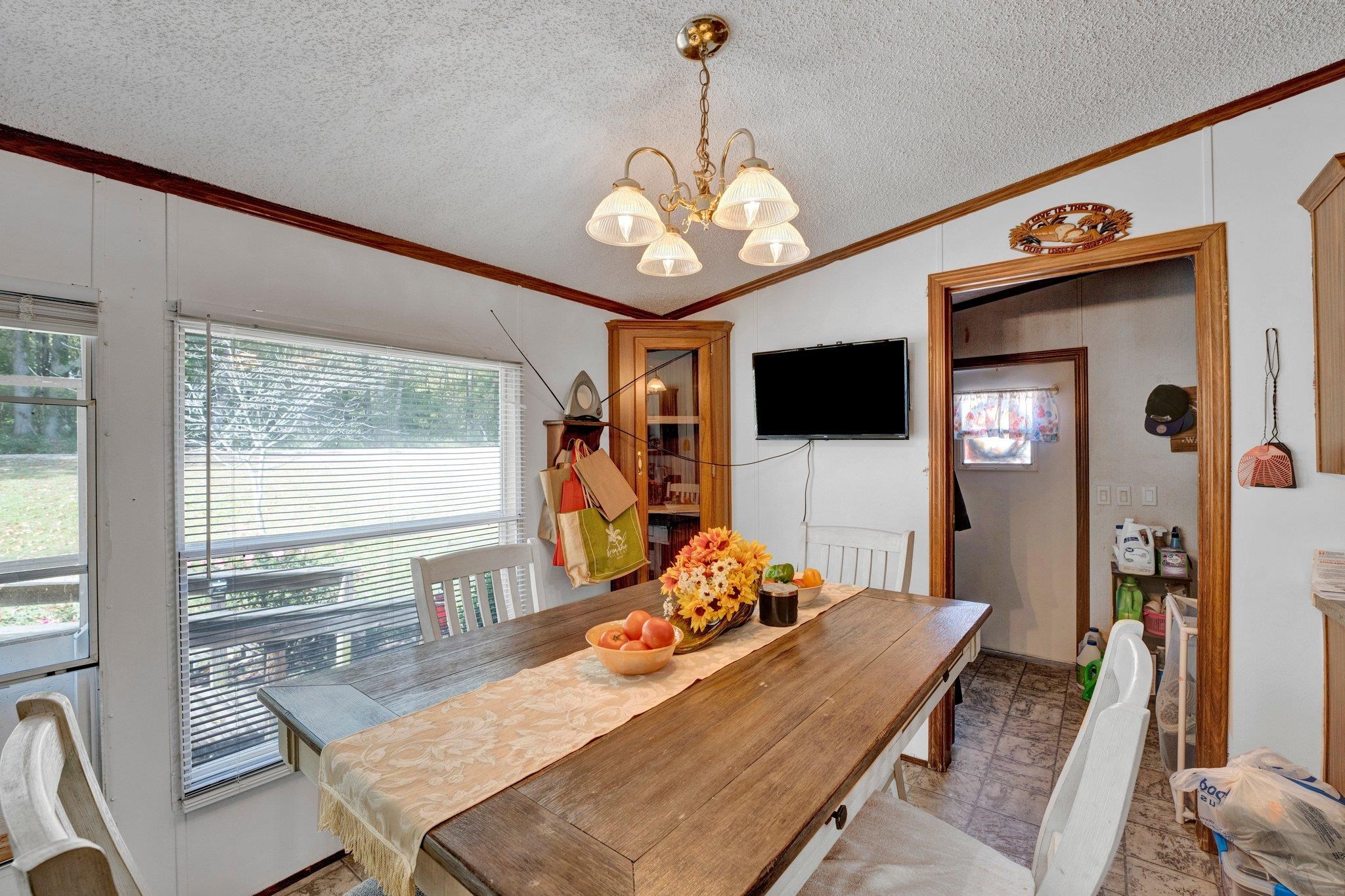 Dining area featuring a chandelier, a textured ceiling, vaulted ceiling, and ornamental molding