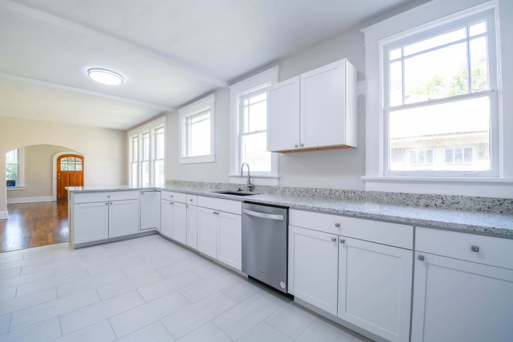 Kitchen featuring white cabinetry, stainless steel dishwasher, sink, and a healthy amount of sunlight