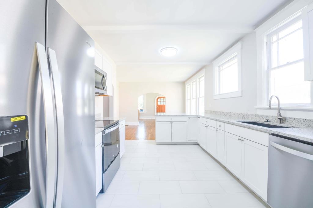 Kitchen featuring white cabinets, stainless steel appliances, sink, and light stone counters