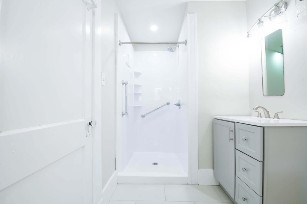 Bathroom featuring a shower, vanity, and tile patterned flooring