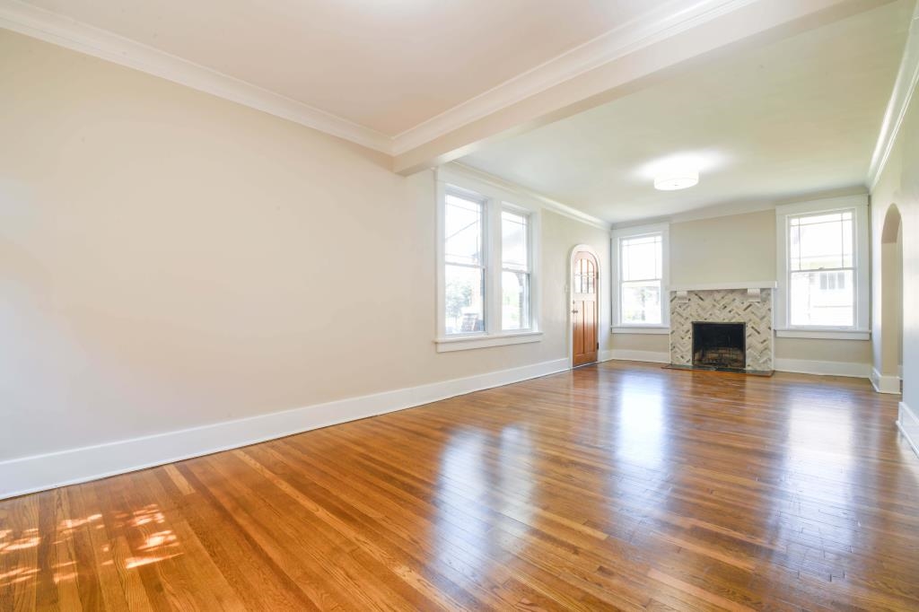 Unfurnished living room with a tiled fireplace, hardwood / wood-style flooring, and ornamental molding