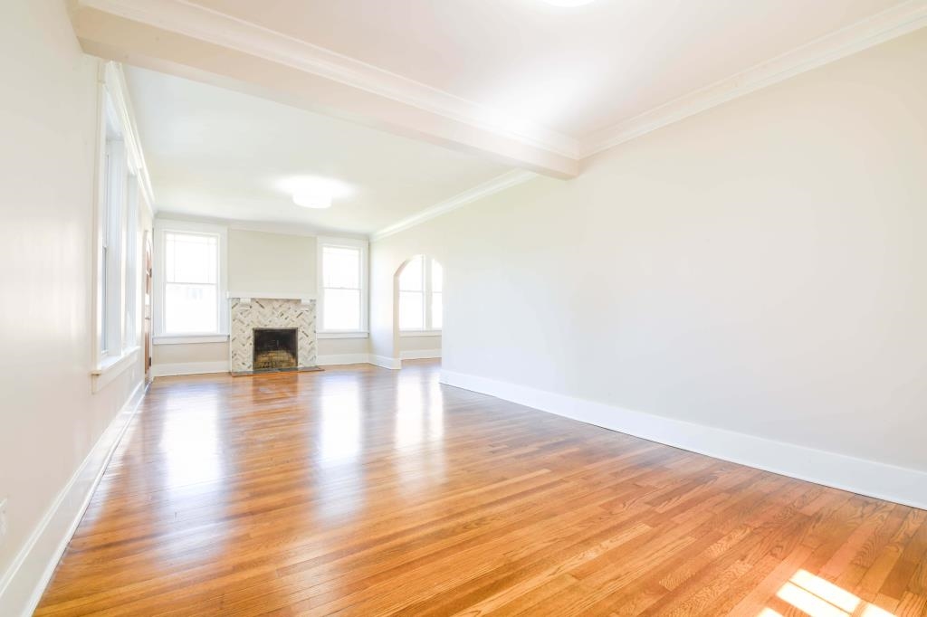 Unfurnished living room with ornamental molding, light wood-type flooring, beam ceiling, and a premium fireplace