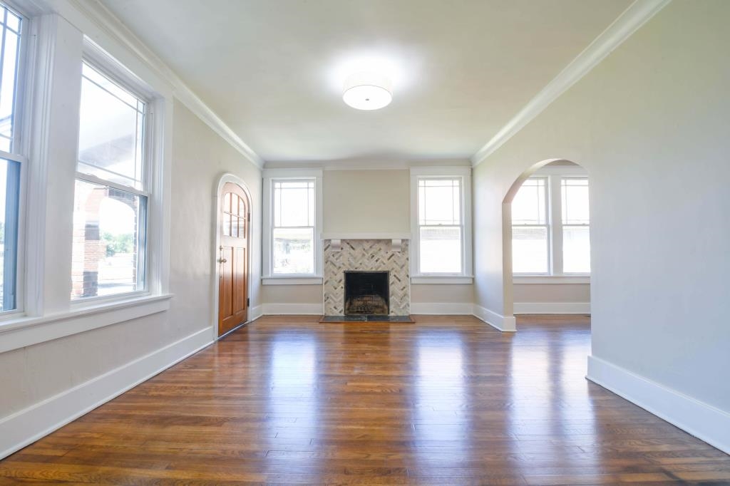 Unfurnished living room featuring dark hardwood / wood-style flooring, ornamental molding, and a fireplace