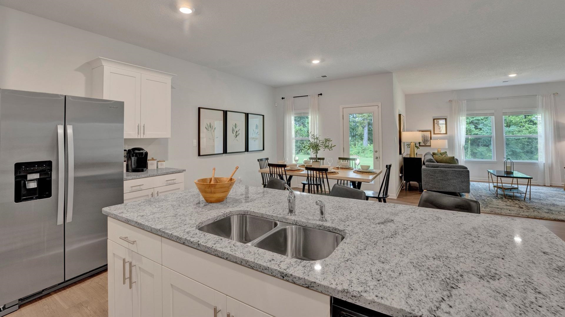 Kitchen with white cabinets, light stone countertops, stainless steel fridge with ice dispenser, and light hardwood / wood-style flooring