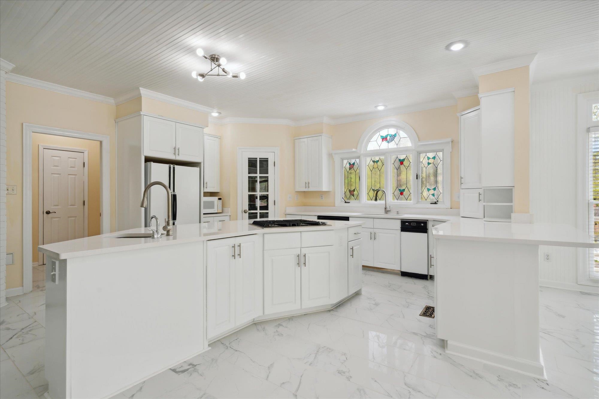 Kitchen with sink, ornamental molding, white appliances, a center island, and white cabinets