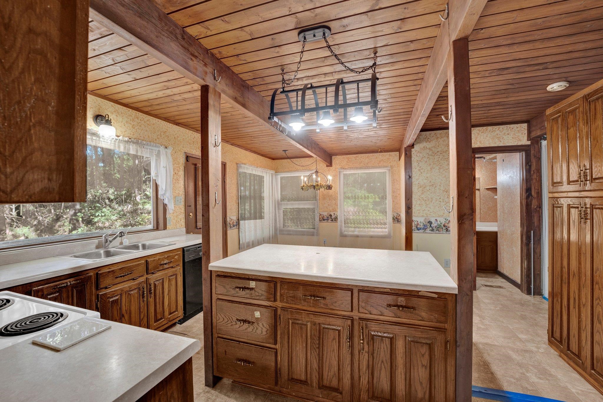 Kitchen featuring wood ceiling, an inviting chandelier, dishwasher, sink, and decorative light fixtures