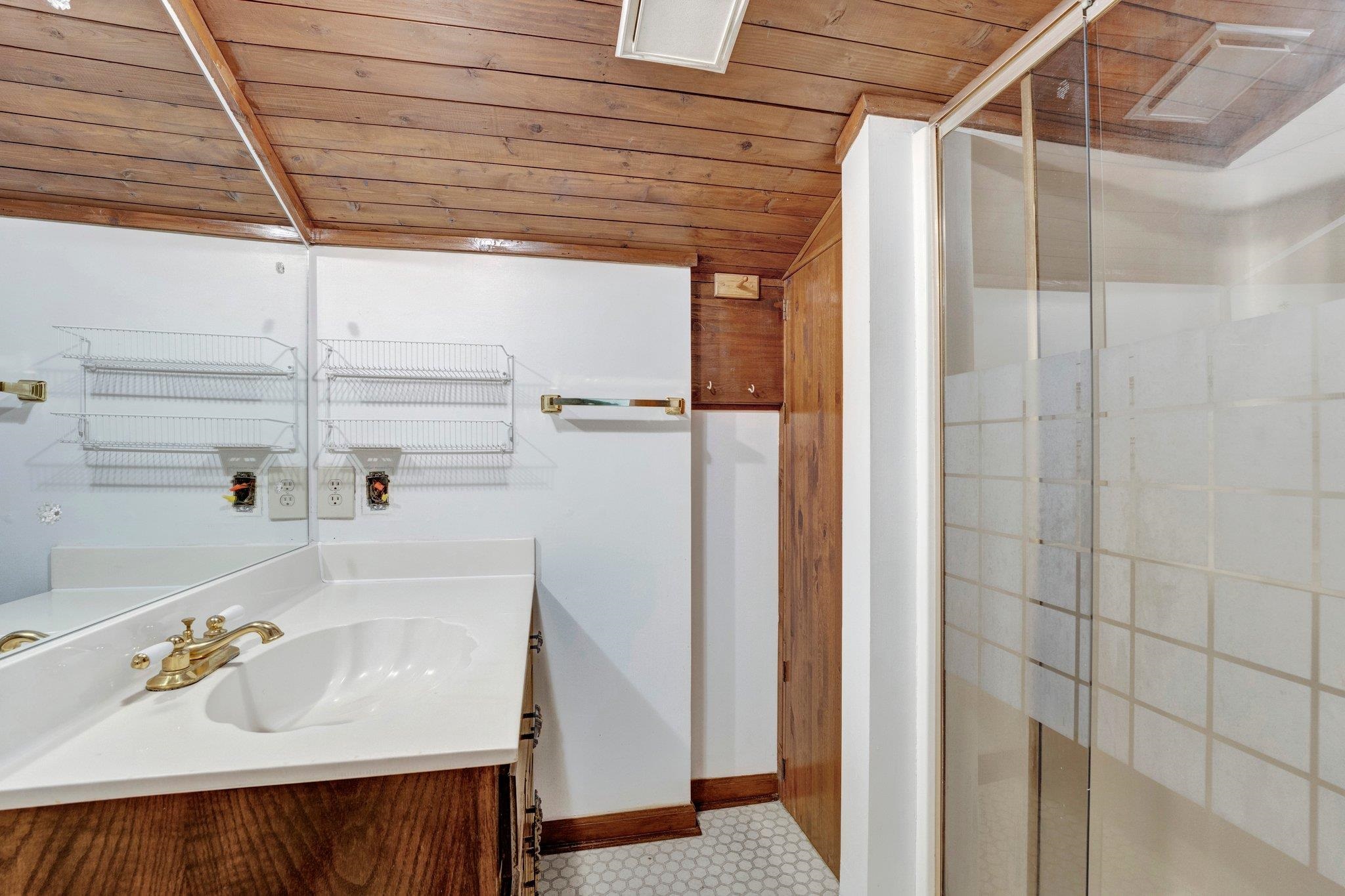 Bathroom with vanity, wooden ceiling, and a shower with shower door