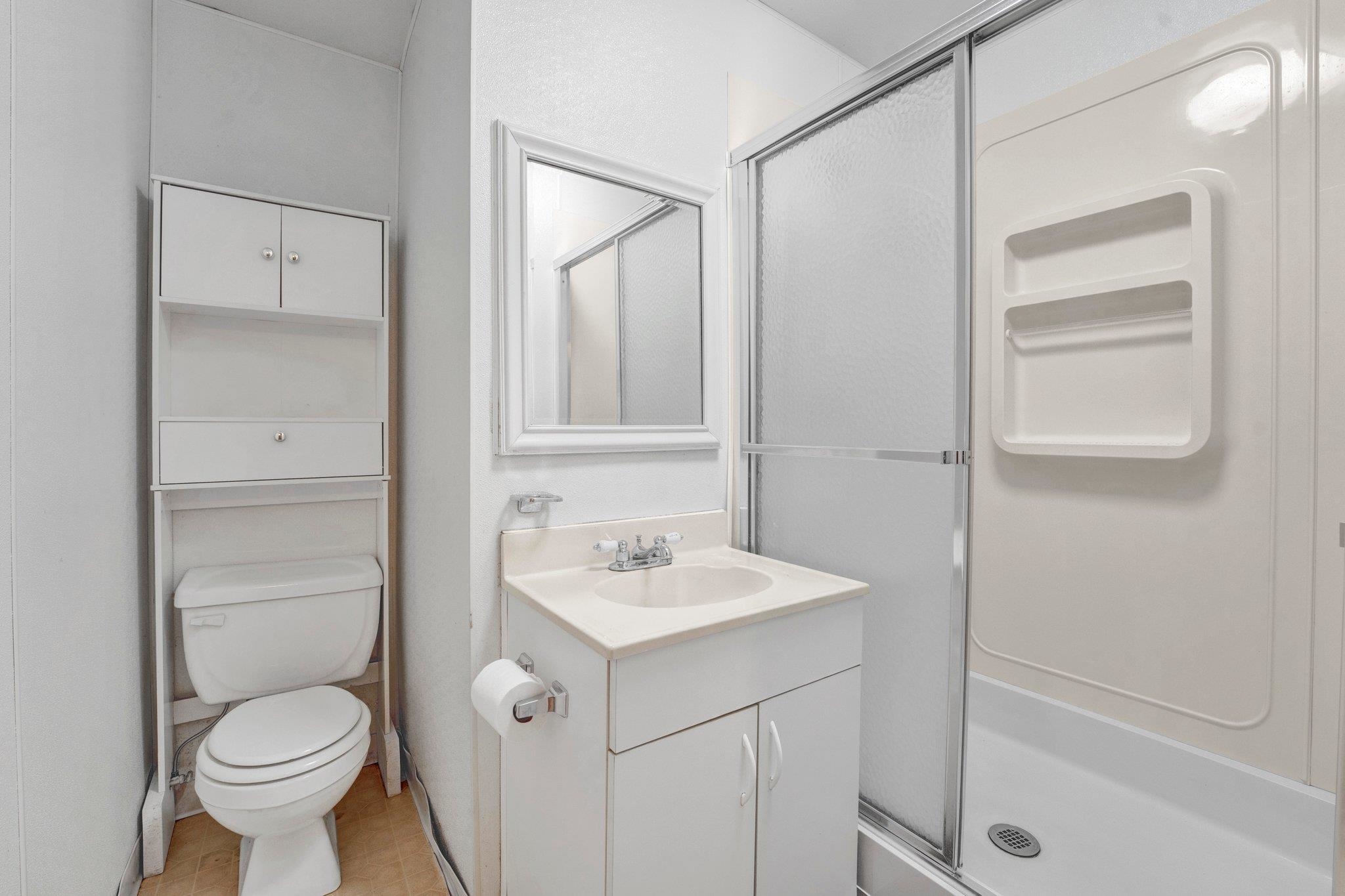 Bathroom with vanity, tile patterned floors, toilet, and a shower with door