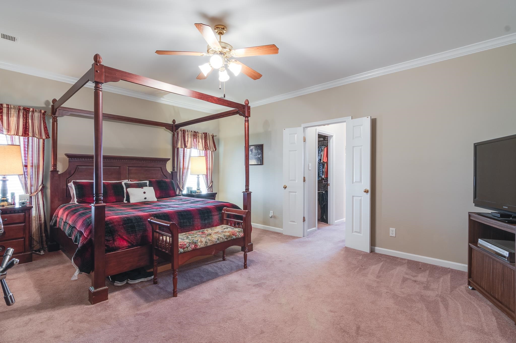 Carpeted bedroom featuring ceiling fan and crown molding