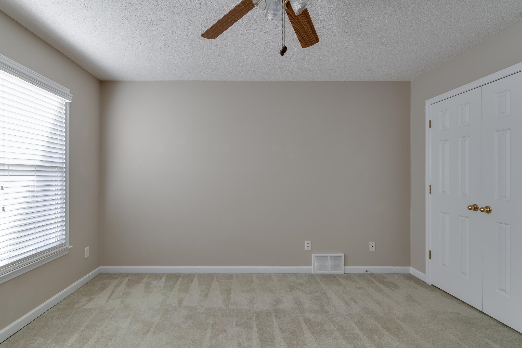 Unfurnished bedroom with a textured ceiling, light colored carpet, and ceiling fan