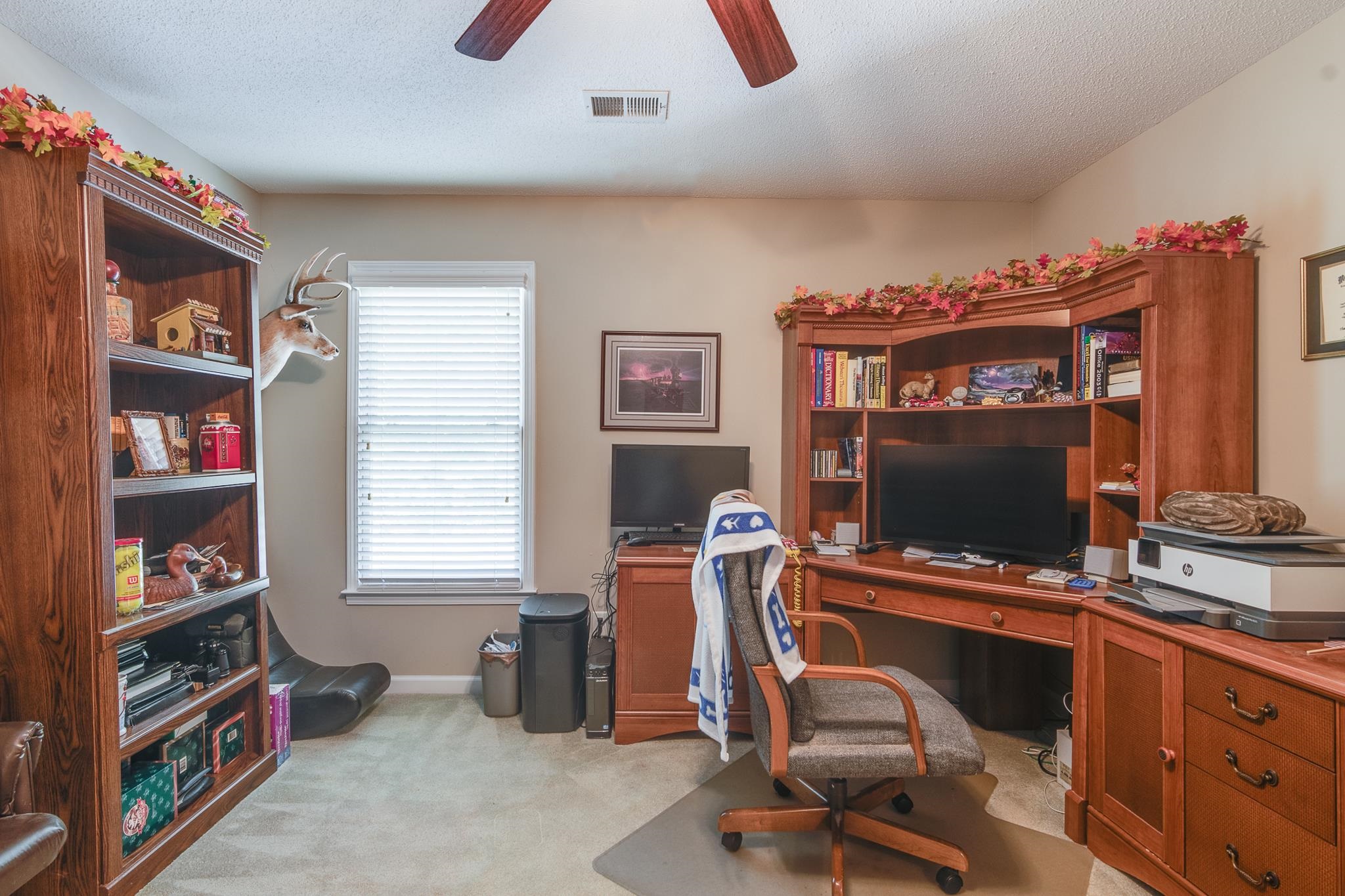 Carpeted office with a textured ceiling and ceiling fan