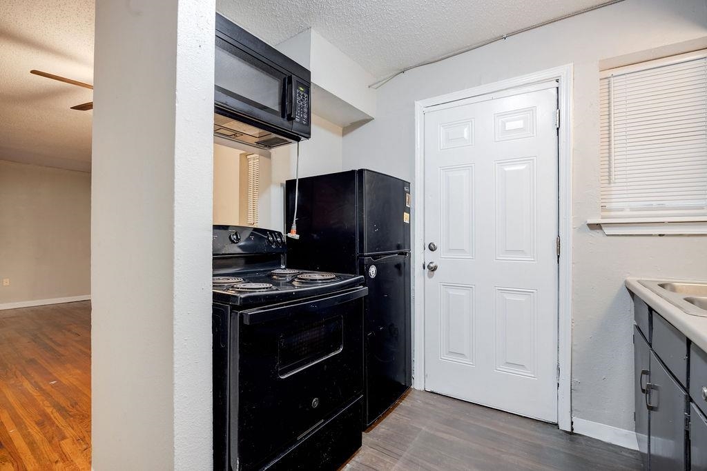 Kitchen with black appliances, dark hardwood / wood-style flooring, a textured ceiling, and ceiling fan