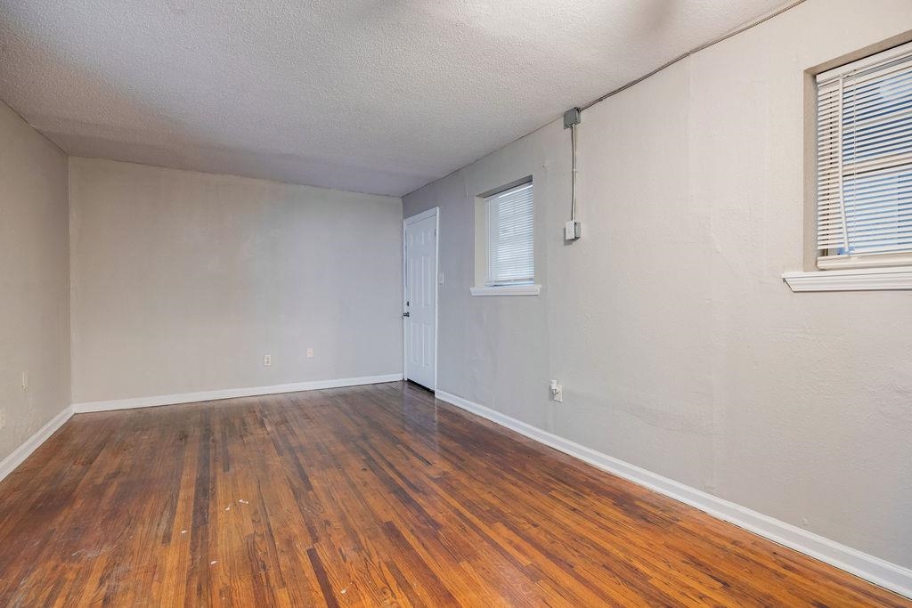 Empty room featuring a textured ceiling and dark hardwood / wood-style floors