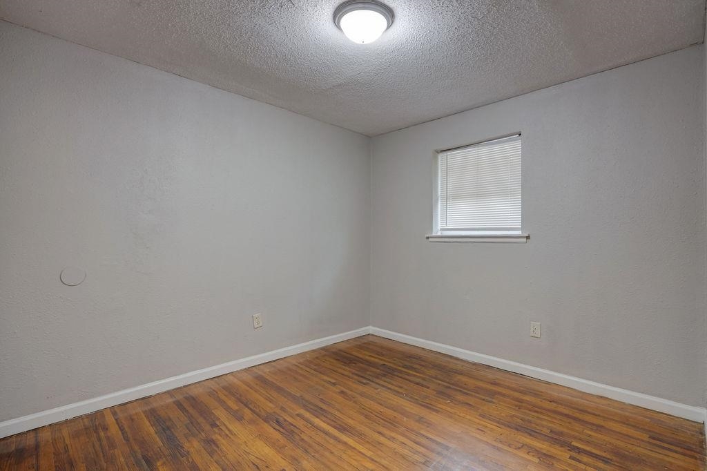 Spare room featuring a textured ceiling and dark hardwood / wood-style floors