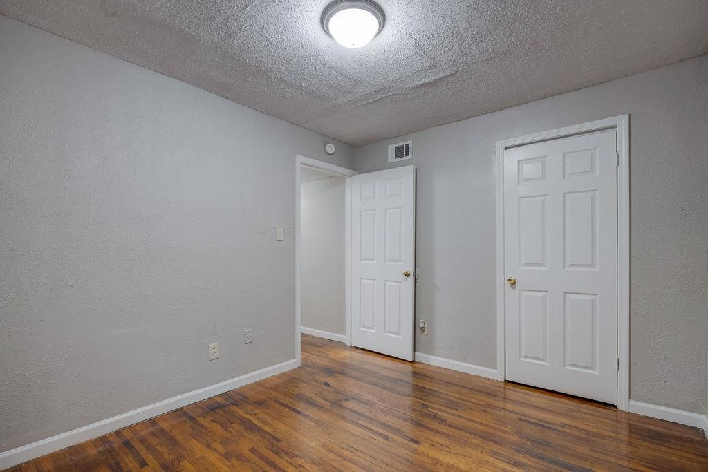 Unfurnished bedroom with dark hardwood / wood-style flooring and a textured ceiling