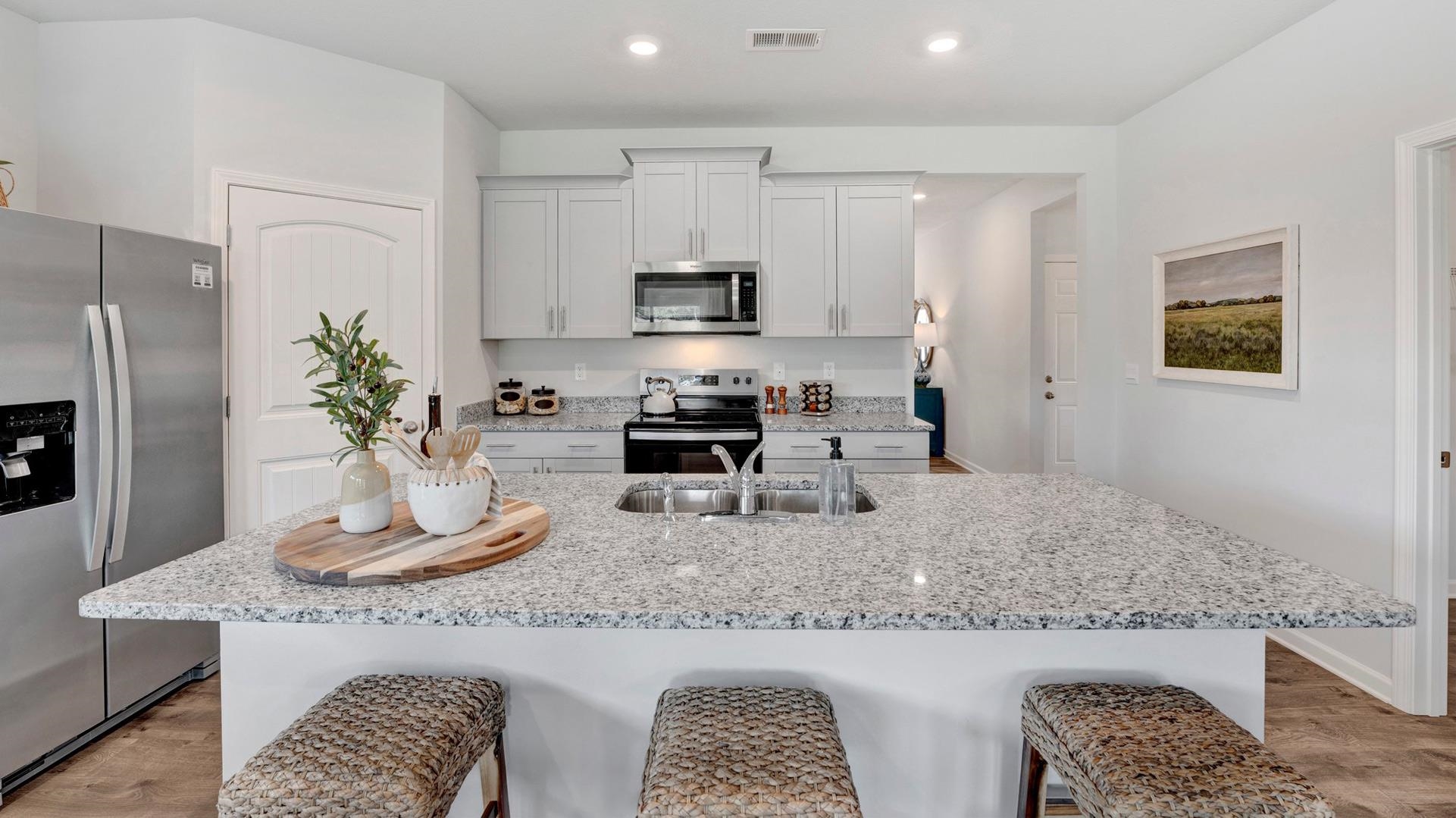 Kitchen with light hardwood / wood-style flooring, appliances with stainless steel finishes, an island with sink, and white cabinets