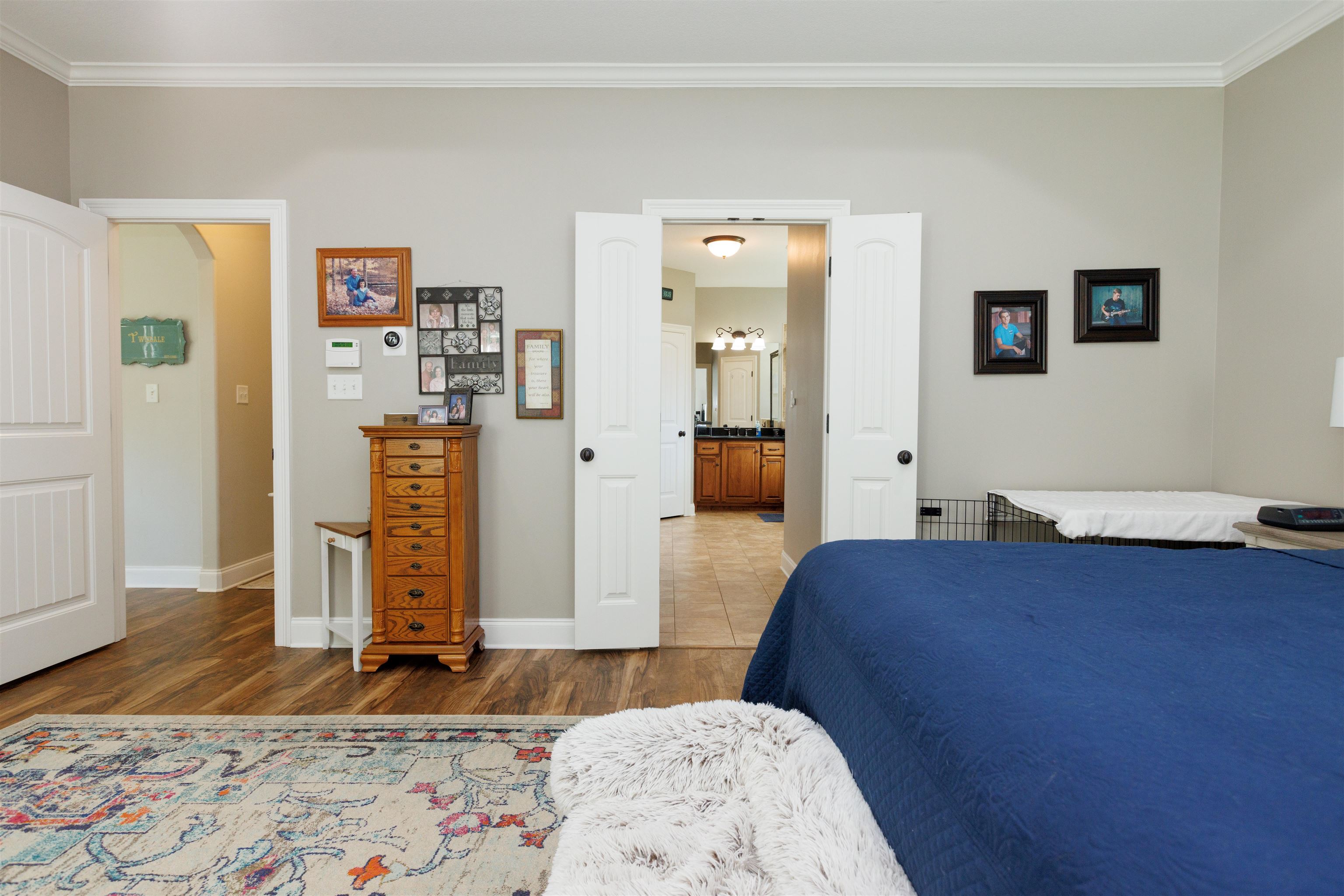 Bedroom with connected bathroom, a chandelier, hardwood / wood-style floors, and ornamental molding