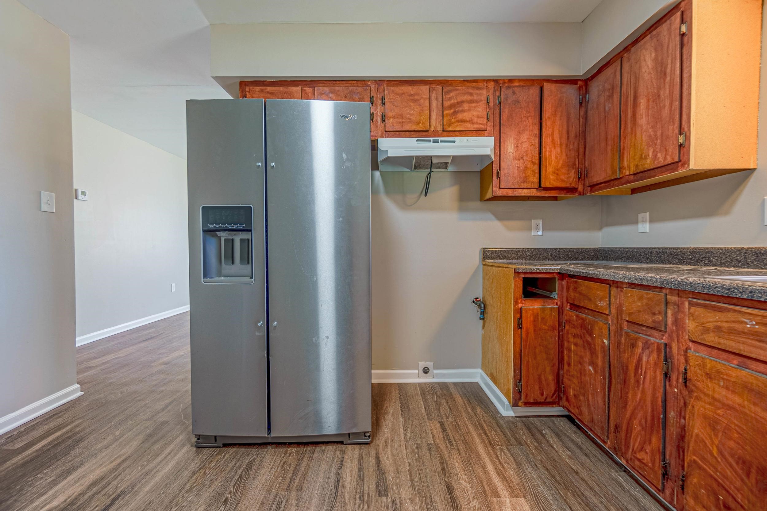 Kitchen featuring dark wood-type flooring and stainless steel refrigerator with ice dispenser