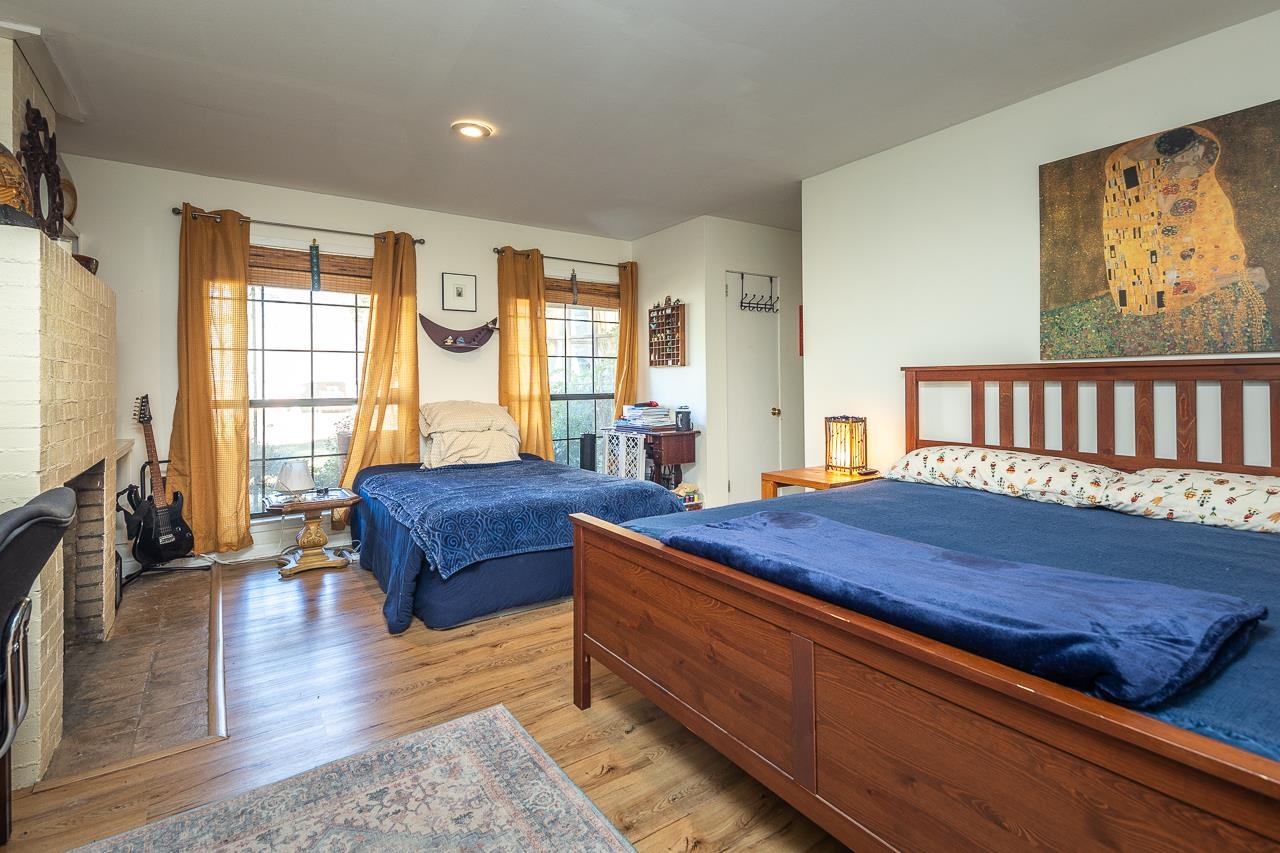 Bedroom featuring a brick fireplace and light wood-type flooring