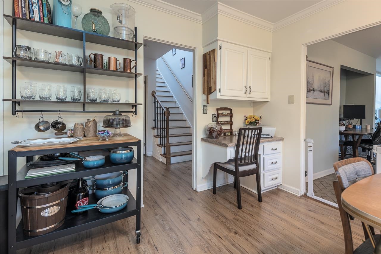 Interior space featuring built in desk, white cabinetry, light hardwood / wood-style flooring, and crown molding