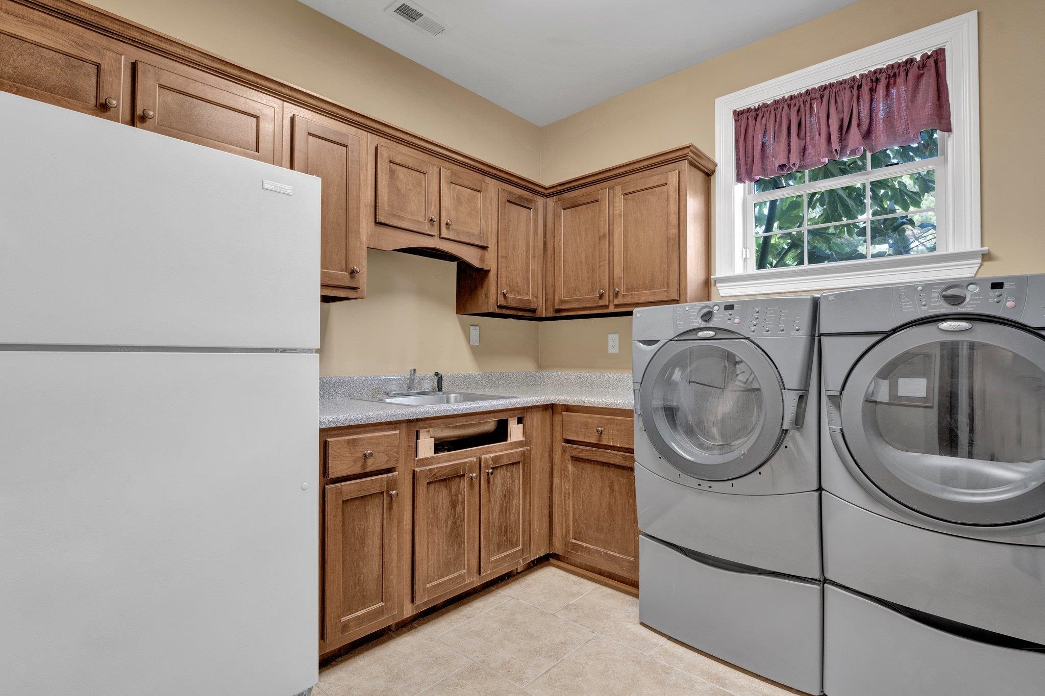 Laundry room featuring sink, independent washer and dryer, and light tile patterned floors