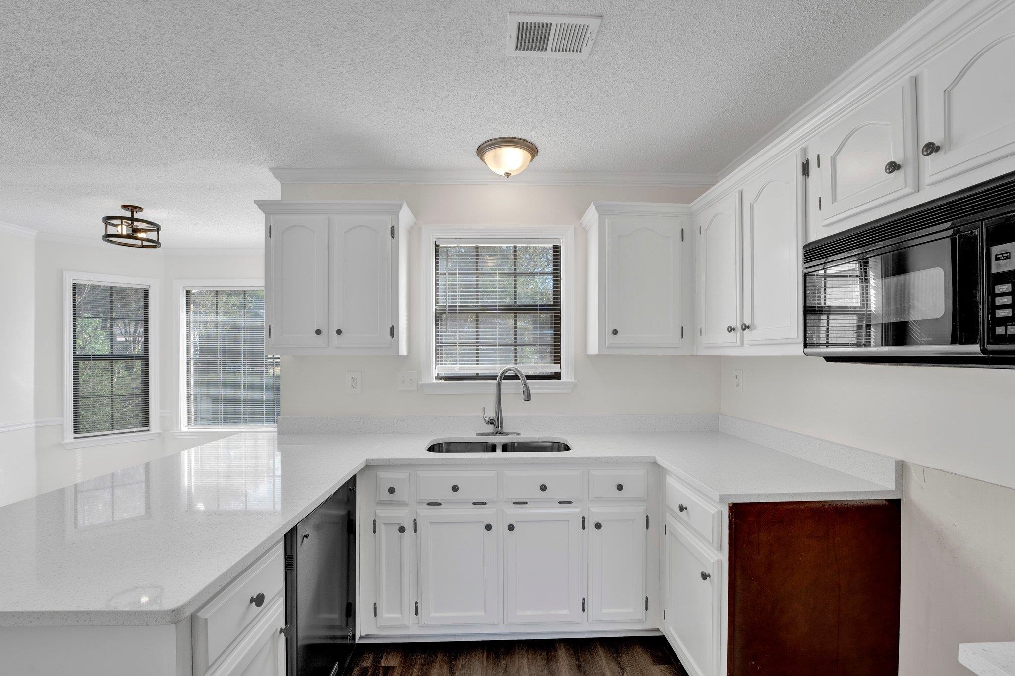 Kitchen featuring a healthy amount of sunlight, sink, and white cabinetry