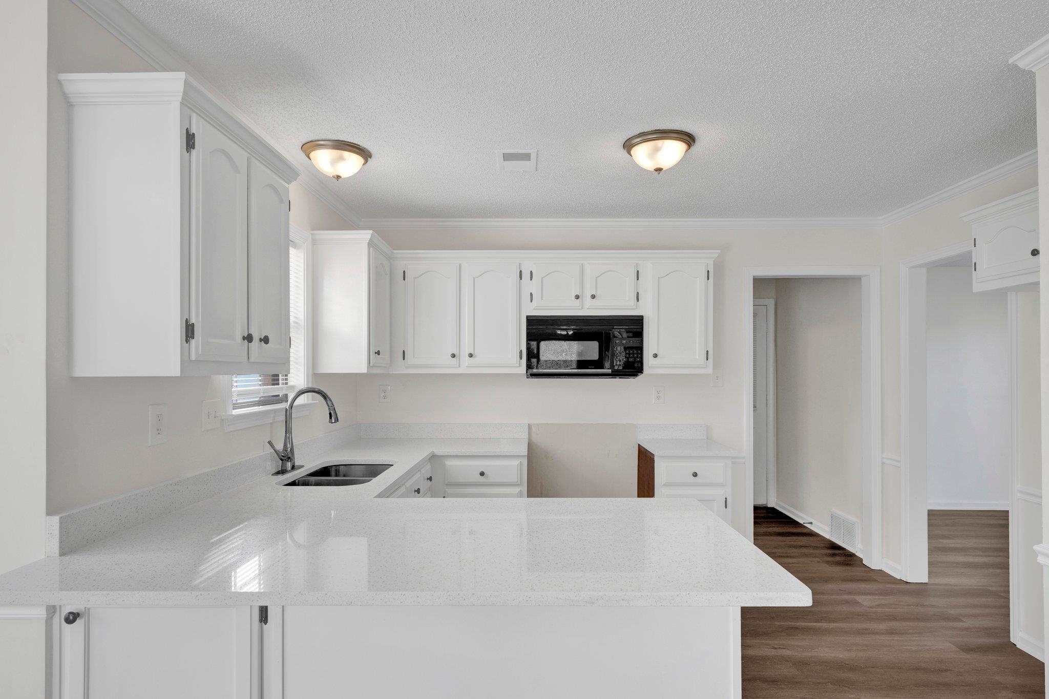 Kitchen featuring white cabinets, sink, dark wood-type flooring, and kitchen peninsula