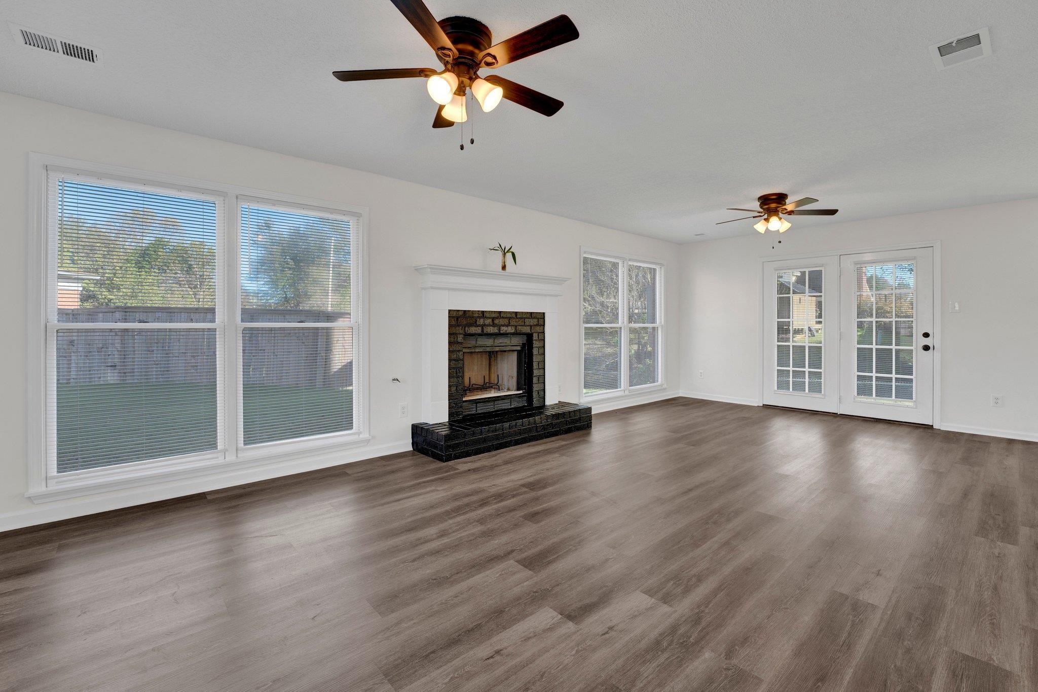 Unfurnished living room with hardwood / wood-style floors, ceiling fan, and a fireplace