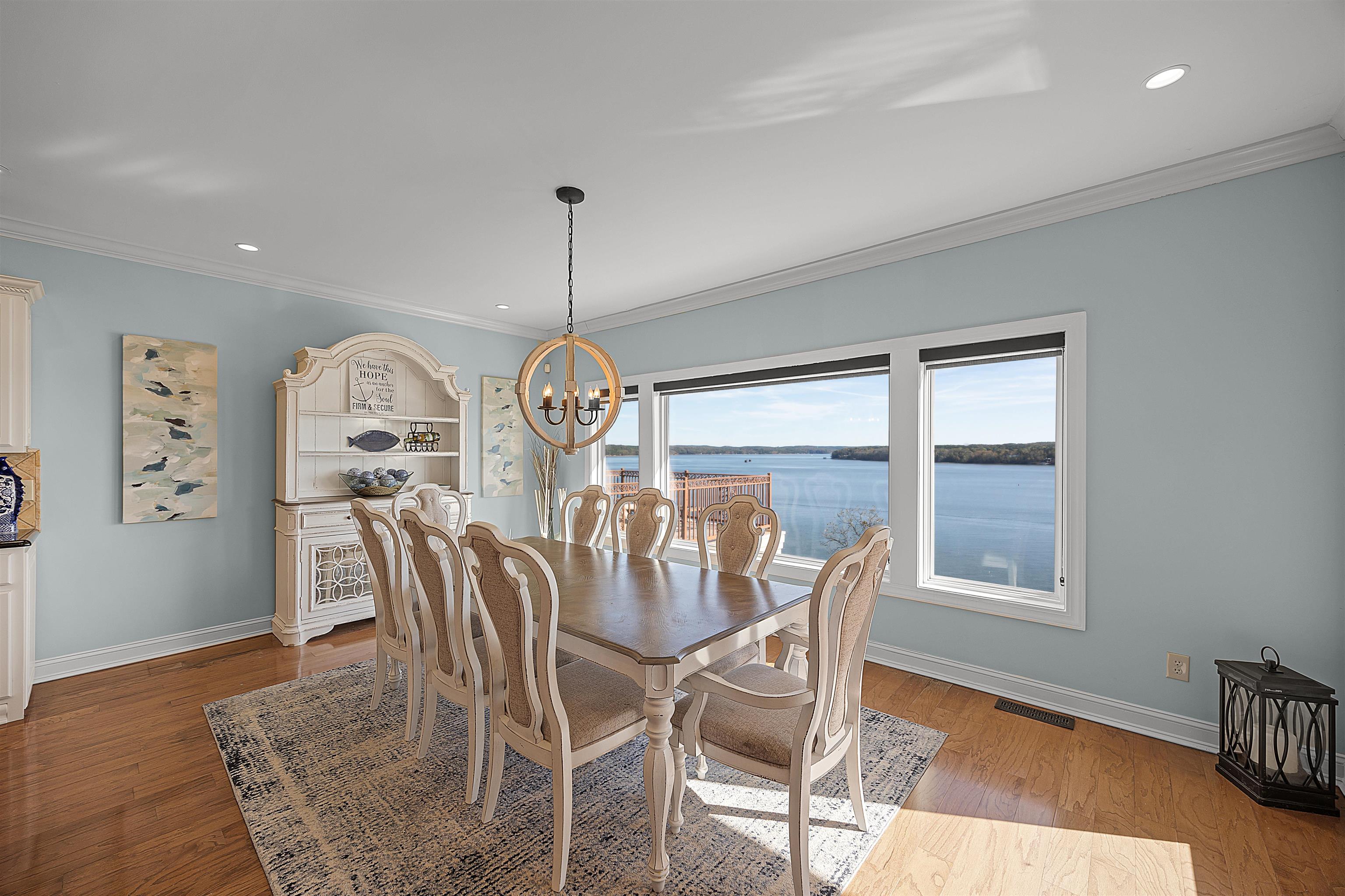 Dining area featuring a water view, a notable chandelier, light hardwood / wood-style floors, and crown molding