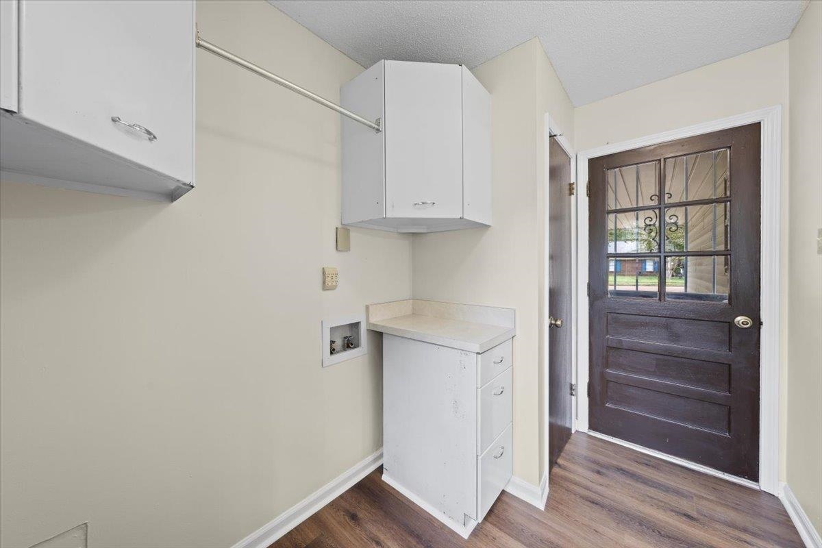 Laundry room with washer hookup, cabinets, a textured ceiling, and dark hardwood / wood-style floors