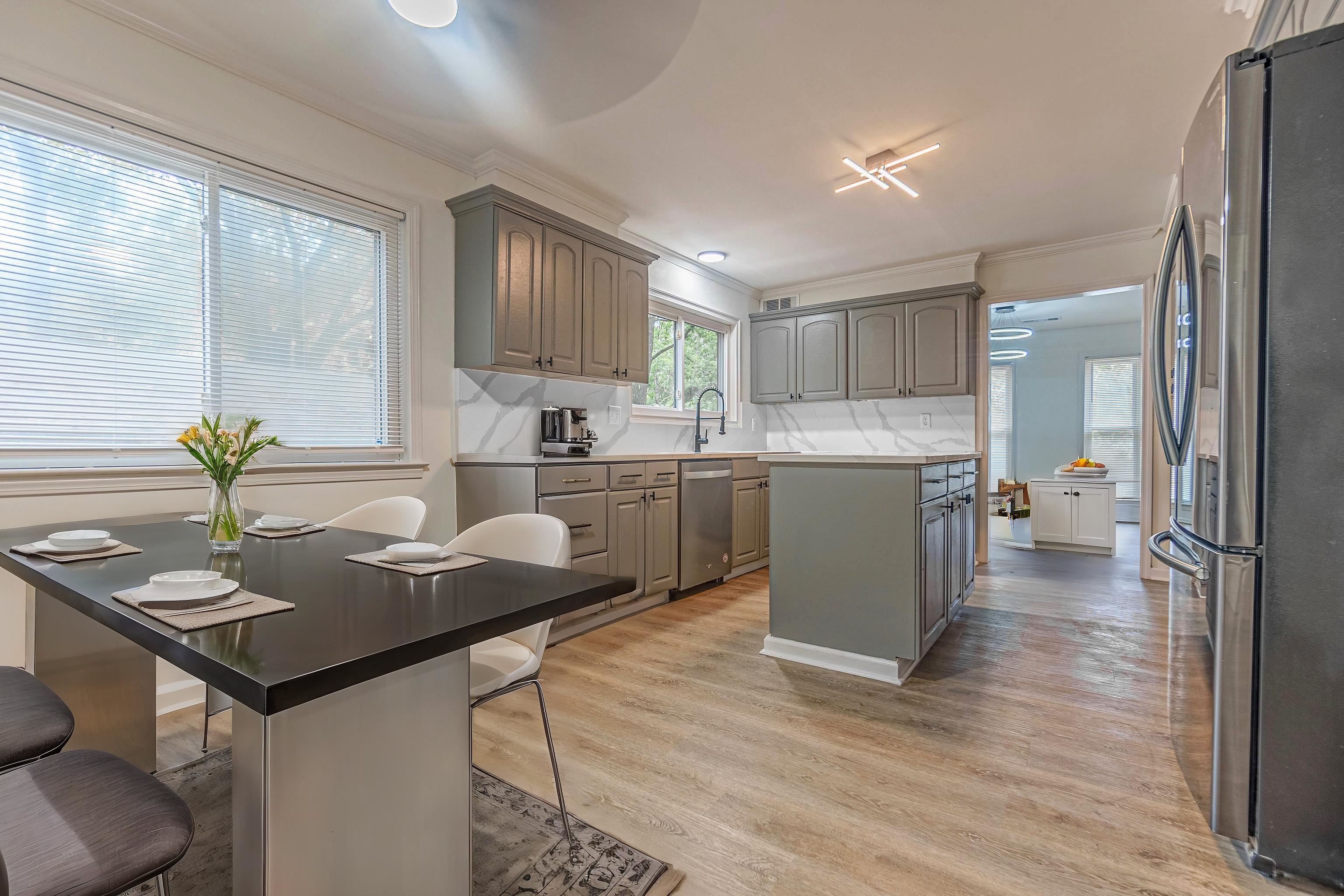 Kitchen with stainless steel appliances, light hardwood / wood-style floors, a kitchen island, gray cabinetry, and decorative backsplash