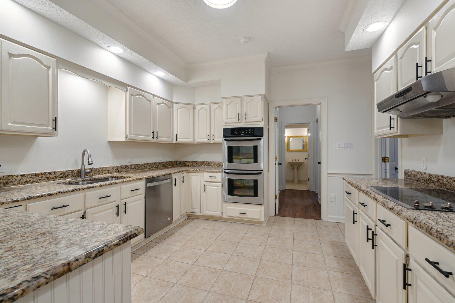 Kitchen with ornamental molding, stainless steel appliances, light tile patterned floors, sink, and white cabinets