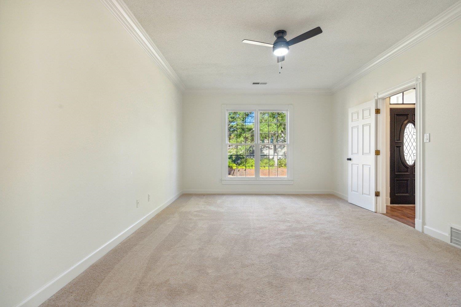 Carpeted spare room featuring ceiling fan, a textured ceiling, and crown molding